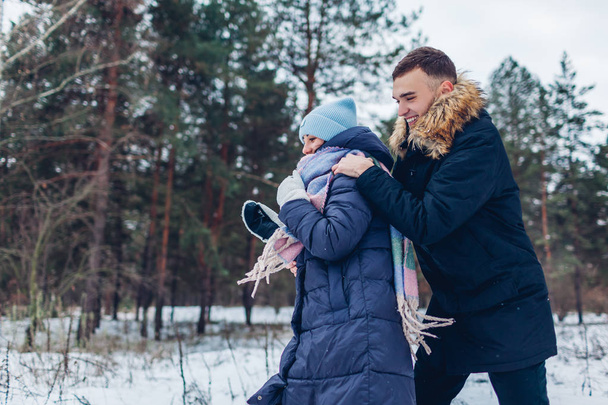 Beautiful loving couple running in winter forest together. People having fun outdoors. Guy trying to catch his girlfriend - Foto, imagen