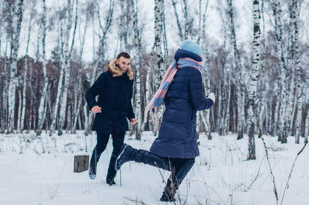 Krásný milující pár běží v zimním lese společně. Lidé, které baví venku. Chlap se snaží chytit svou přítelkyni - Fotografie, Obrázek