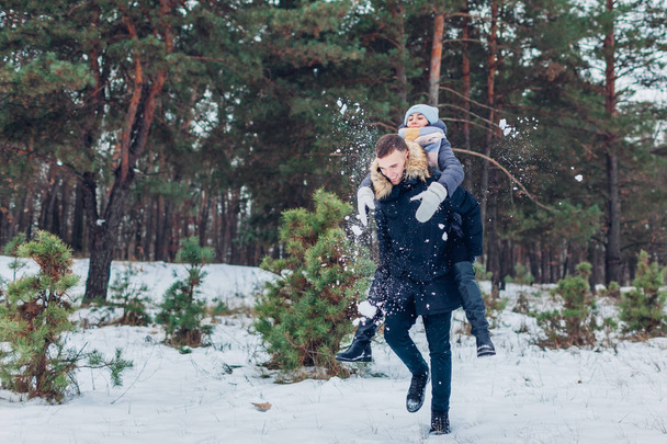Un tizio che da 'alla sua ragazza un passaggio nella foresta invernale. Giovane coppia amorevole divertirsi all'aperto. Persone felici relax
 - Foto, immagini