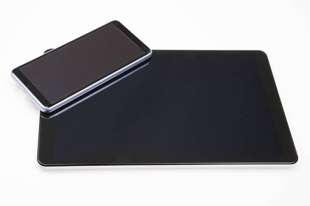 teléfono acostado encima de la tableta con pantalla táctil aislada sobre fondo blanco
 - Foto, imagen