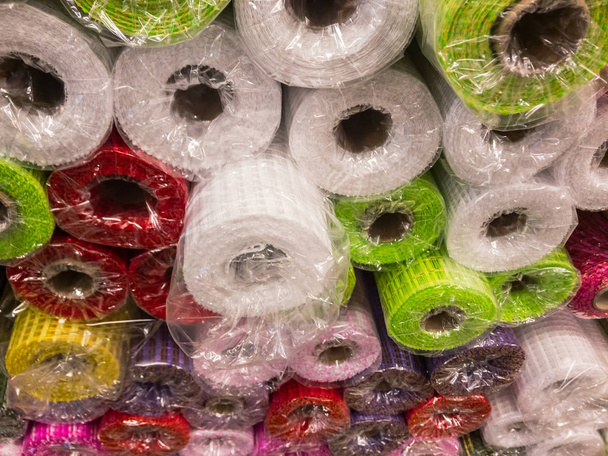 Rolos de papel decorativo texturizado de diferentes cores na prateleira da loja
 - Foto, Imagem