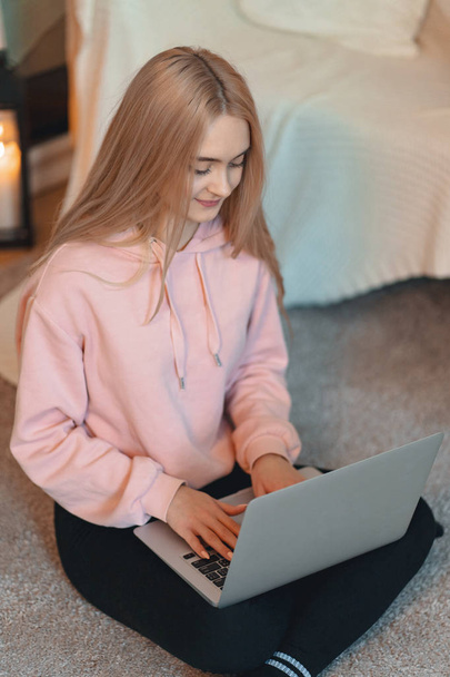 Sorridente bella donna che lavora su un computer portatile mentre seduto sul pavimento in casa
. - Foto, immagini