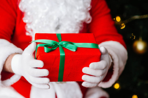Red gift in Santa Claus hands near Christmas background - Photo, Image