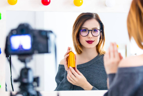 Giovane blogger caucasica donna che applica cosmetici presso la fotocamera per il sito di condivisione video. Posizione di casa vicino a uno specchio
 - Foto, immagini