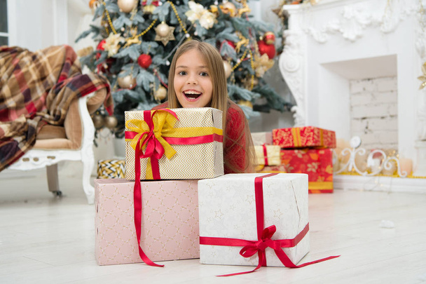 Child enjoy the holiday. Decorate your Christmas with joy. Christmas tree and presents. Happy new year. Winter. xmas online shopping. Family holiday. The morning before Xmas. Little girl - Foto, Imagen