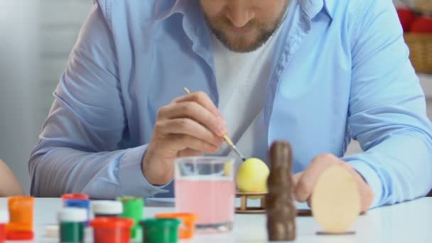 Father and daughter preparing for Easter, drawing eggs with colorful paints - Imágenes, Vídeo