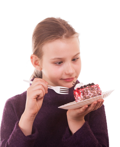 Досить молода дівчина дивиться торт на білому тлі
 - Фото, зображення