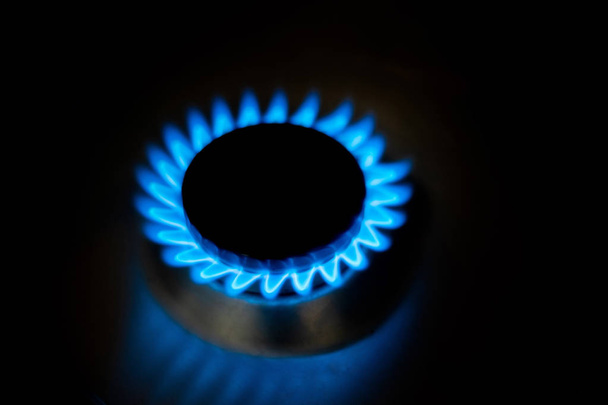 Gas natural quemando llamas azules sobre fondo negro en casa
 - Foto, imagen