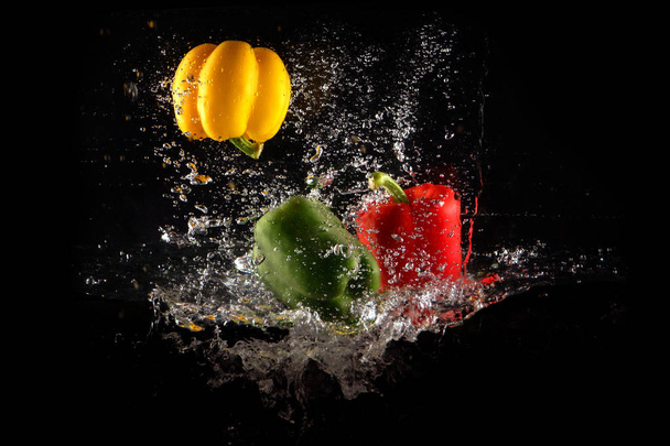 Fresh Green, Yellow and Red Bell Peppers with Water Splash and Bubble Isolated. Colorful Copy Space. Colored Paprika Dropped into Water on Black Background Great For Any Use. - Fotó, kép