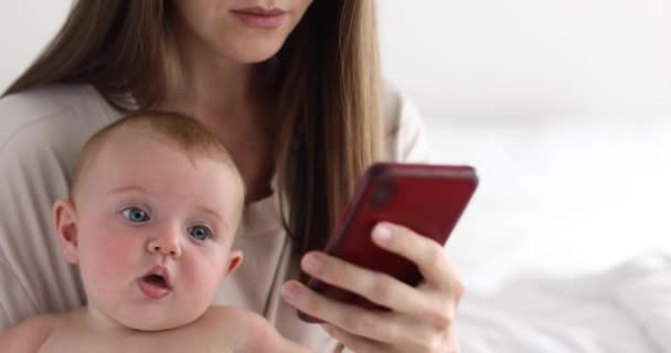 Mother with little daughter uses smartphone - Footage, Video