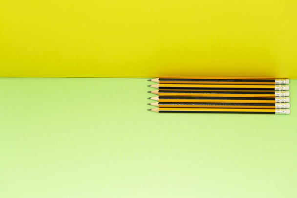 Pattern composition of yellow pencils on yellow-green background. Minimalist isometric concept - Foto, imagen