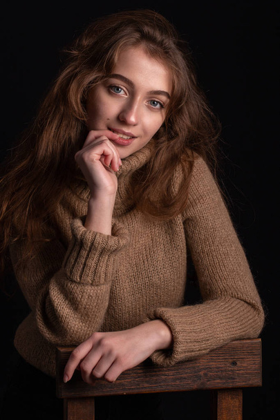 Közelről egy pulóvert, a sötét háttér előtt egy fiatal lány portréja - Fotó, kép