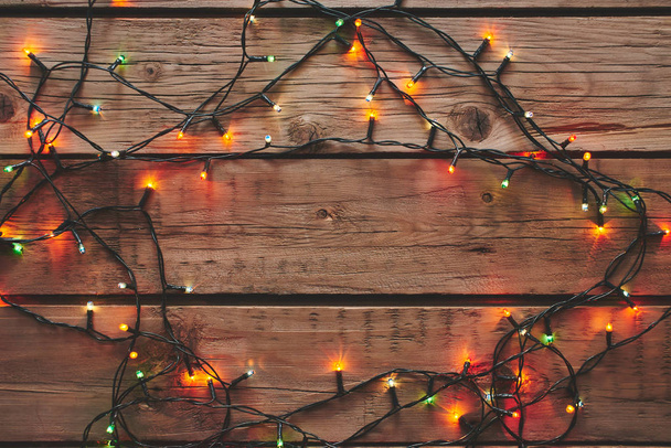 Frame made from christmas garland on wooden background. - Foto, afbeelding