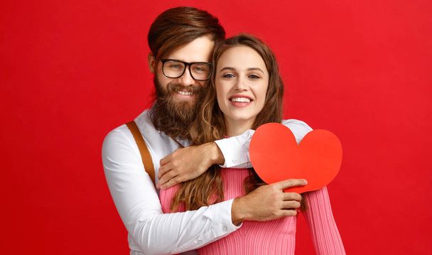 Концепція дня Валентина. щаслива молода пара з серцем, квітами, подарунком на червоному фоні
 - Фото, зображення