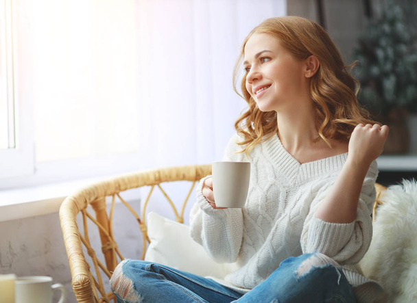 happy young woman drinking morning coffee by the window in winter - Фото, зображення