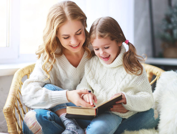щаслива родина мама читає книгу дитині дочки вікном взимку морнін
 - Фото, зображення