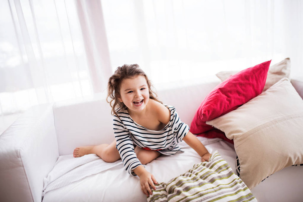 A small happy girl in striped T-shirt at home having fun. - Valokuva, kuva