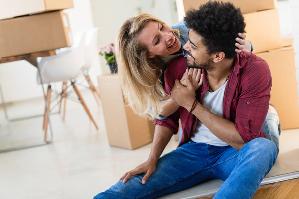Young couple in love unpacking cardboard boxes at new home moving in concept - Foto, afbeelding