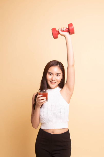 Young healthy Asian woman with dumbbell and  tomato juice   on beige background - Foto, Bild