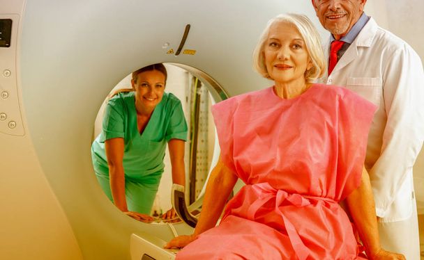 Mujer de 60 años lista para someterse a una resonancia magnética, asistida por dos médicos tranquilizadores
. - Foto, imagen