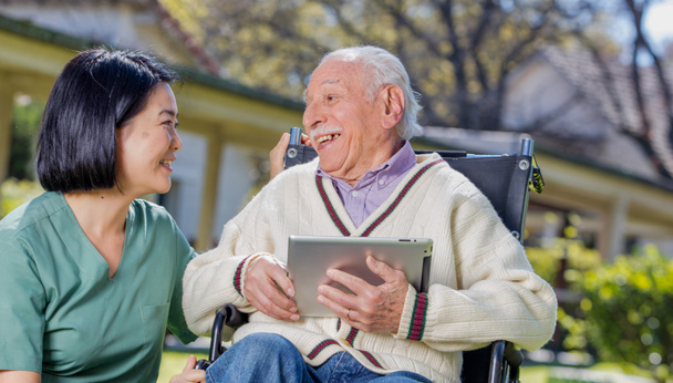 Verpleegkundige gebruik van Tablet PC uit te leggen aan oudere mensen buiten. - Foto, afbeelding