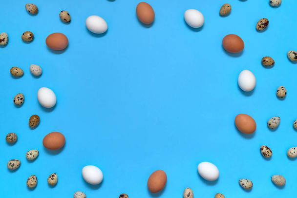 Frame of white, brown and quial eggs on blue background, copy space. Healthy food concept. Top view, flat lay. Easter eggs. Happy Easter concept - Foto, Imagen