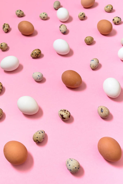 Hen white and brown eggs and quail eggs on pink background, copy space. Healthy food concept. Top view, flat lay. Easter eggs. Happy Easter concept - Foto, afbeelding