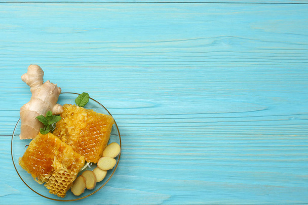 healthy background. honey, honeycomb, lemon, tea, ginger on blue wooden table. Top view with copy space - Foto, Imagem