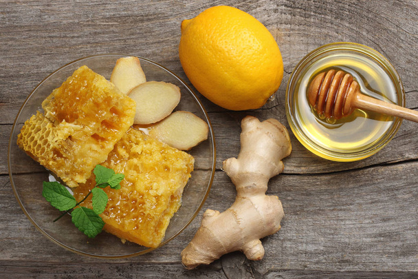 healthy background. honey, honeycomb, lemon, tea, ginger on old wooden table. Top view with copy space - Foto, immagini