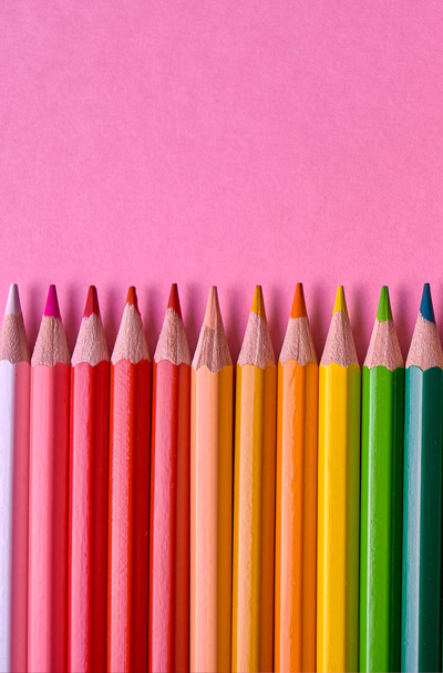 Color pencils on pink pastel background, close up. Set of colorful pencils, copy space. Crayons. Top view, flat lay. Back to school, college concept. Abstract background - Photo, image