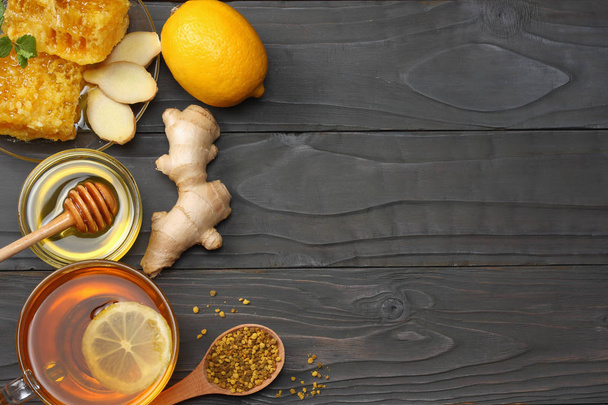 healthy background. honey, honeycomb, lemon, tea, ginger on dark wooden table. Top view with copy space - Foto, immagini