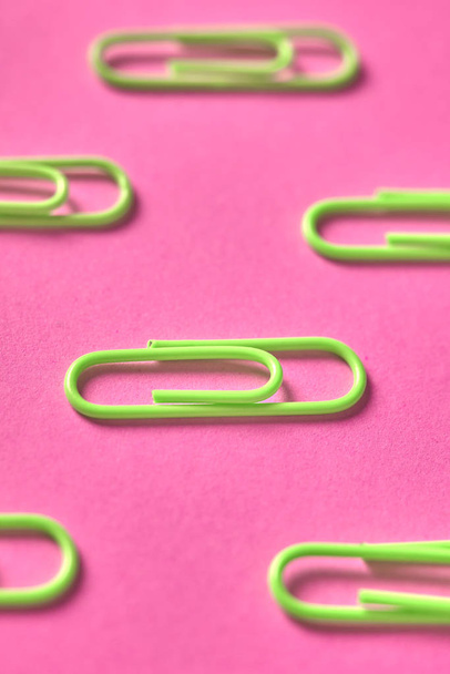 Lime green paper clips isolated on pink background, close up, copy space. Top view, flat lay. Back to school, college, education concept - Zdjęcie, obraz