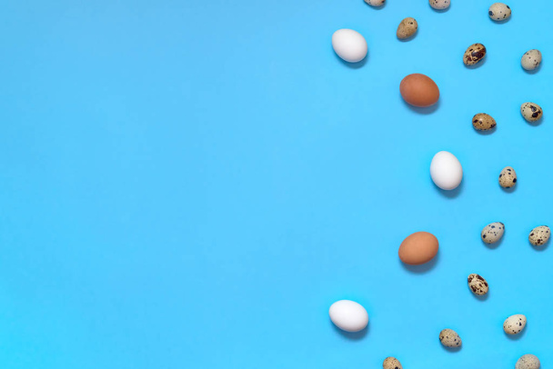 Border of white, brown and quial eggs on blue background, copy space. Healthy food concept. Top view, flat lay. Easter eggs. Happy Easter concept - Photo, image