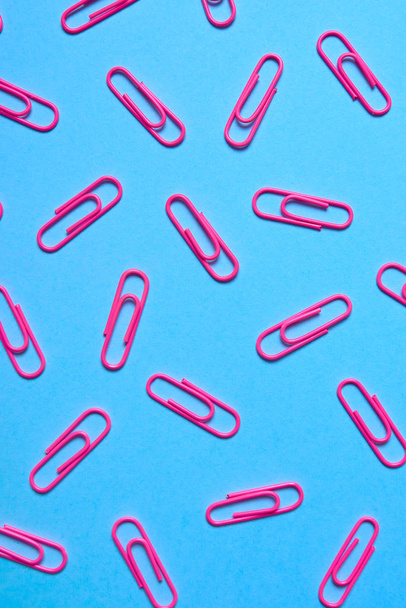 Pink paper clips on pastel blue background, copy space. Top view, flat lay. Back to school, college, education concept. Collection of colorful paperclips. Abstract background - Fotografie, Obrázek