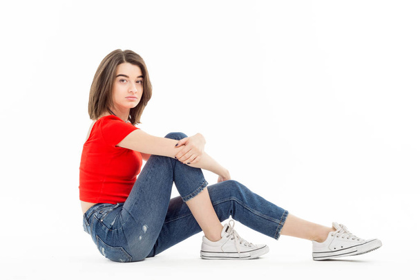 Teenage girl sitting on white background - Fotó, kép