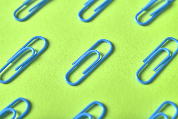 Blue paper clips isolated on green background, close up, copy space. Top view, flat lay. Back to school, college, education concept - Foto, imagen