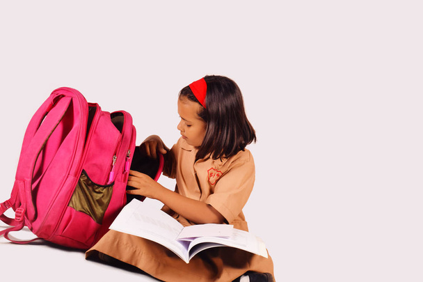 Little girl in school uniform studying with school bag on the side.  Pune, Maharashtra - 写真・画像
