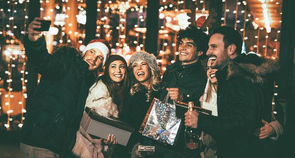 Mladí veselí přátelé slaví Vánoce na zářící město ulice - Fotografie, Obrázek
