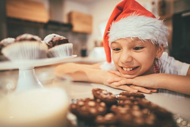 dívka v santa hat při pohledu na desku s cookies  - Fotografie, Obrázek