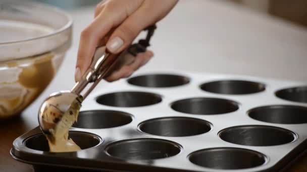 Příprava pečení muffinů. Těsto se dělí na papírových kelímků s kouskem čokolády. Detail muffin pečicího plechu.. - Záběry, video