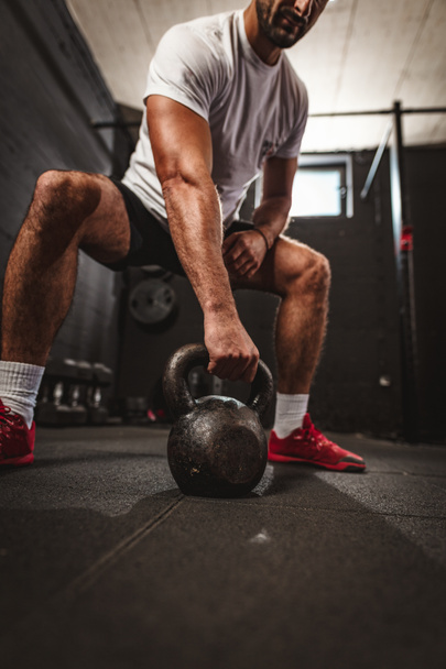Young muscular man doing hard exercise with kettlebell on cross training at gym - Fotoğraf, Görsel