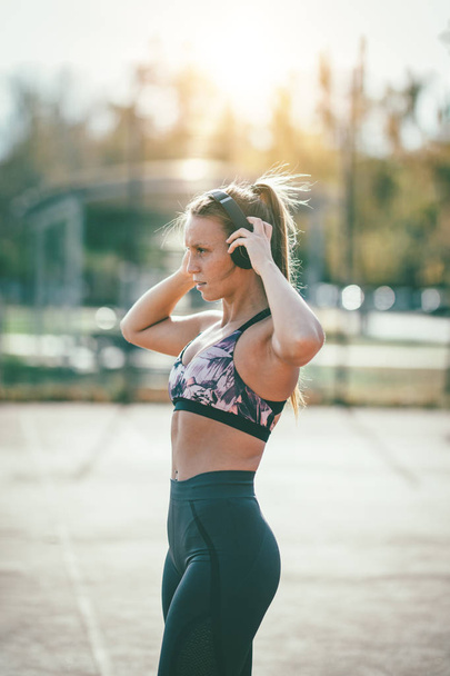 jonge vrouw runner atleet koptelefoon zetten tijdens de voorbereiding op het uitvoeren - Foto, afbeelding