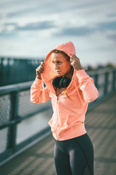 young sport woman dressing up sweatshirt and preparing for morning workout  - Photo, Image