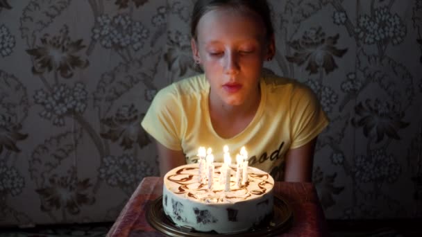 Młoda dziewczyna zdmuchujące świeczki na urodzinowym torcie - Materiał filmowy, wideo