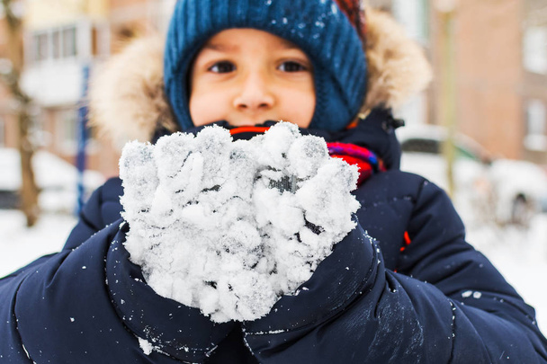 chłopak pokazuje rękawice w śniegu. Zimowy spacer - Zdjęcie, obraz