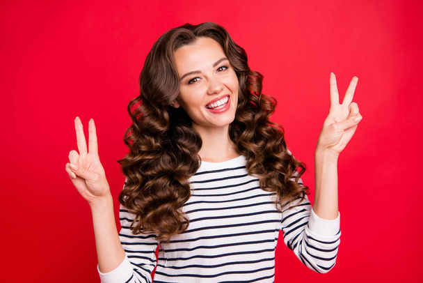Close up portrait of charming cute she her girl with long wave hair fingers v-sign hippie smiling sincere wearing white striped pullover isolated on red bright vivid background - Foto, immagini