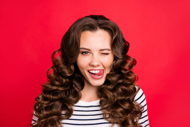 Close up portrait of cheerful attractive she her girl with flirt touching lower lip by tongue amazing wave hair settled on shoulders white striped pullover isolated on red bright vivid background - Φωτογραφία, εικόνα