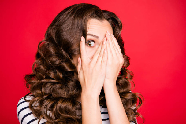 Close up portrait of closing full of fear face attractive looking she her girl watching movie horror only with one eye white striped pullover isolated on red vivid background - Foto, Imagen