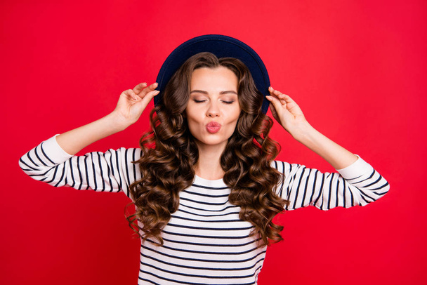 Portrait of nice sweet lovely tender attractive positive wavy-haired lady wearing striped pullover touching sunhat closed eyes isolated over bright vivid shine red background - Фото, изображение