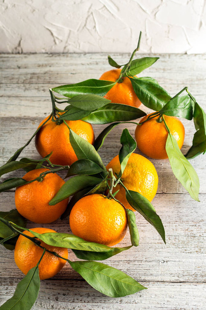 molti mandarini arancioni con foglie verdi su sfondo di legno bianco
 - Foto, immagini